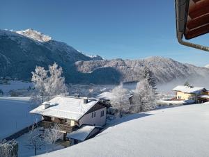 a house covered in snow with mountains in the background at Ferienwohnung Lienbacher in Abtenau