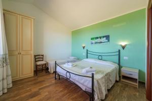 a bedroom with two beds and a chair at Casa Mirto con piscina e vista mare in Aglientu