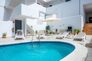 a pool with chairs and a table and an umbrella at White suites in Cala d´Or +20 photos