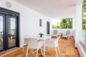 a dining room with white chairs and a table at White suites in Cala d´Or