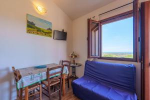 a living room with a table and a blue couch at Casa Mirto con piscina e vista mare in Aglientu