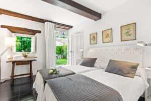 two beds in a bedroom with a desk and a window at Apartamento 1 Casa Las Indianas in Selores