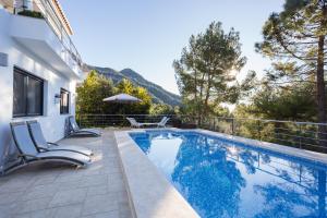 a swimming pool with two chairs next to a house at Mountain View Villa in Bárig