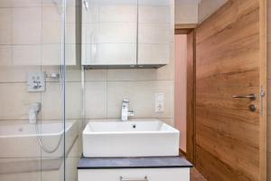a bathroom with a white sink and a glass door at Good Life Top 3 in Saalbach-Hinterglemm