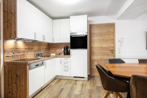 a kitchen with white cabinets and a wooden table at Good Life Top 3 in Saalbach-Hinterglemm