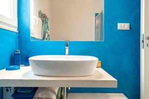 a bathroom with a white sink and a blue wall at Agrumeto sul mare in Ostuni +14 photos