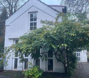 a white house with a tree in front of it at Oberneulander Gästehaus in Bremen