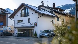 a white building with a car parked in front of it at App Dolomiten Villa Colli in Valdaora