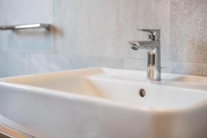 a white sink with a faucet in a bathroom at App Dolomiten Villa Colli in Valdaora