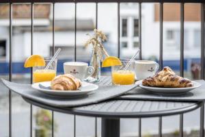 a table with plates of pastries and cups of orange juice at App Dolomiten Villa Colli in Valdaora +9 photos