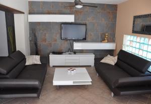 a living room with two black couches and a tv at Villa with private pool - near golf in San Miguel de Salinas