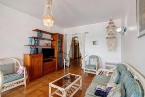 a living room with a couch and chairs and a tv at Beachfront Apartment T2 in Quarteira