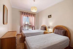 a bedroom with two beds and a window at Beachfront Apartment T2 in Quarteira