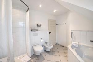 a white bathroom with a toilet and a bath tub at Gut Rattelvitz - Parterre Ost in Gingst +37 photos