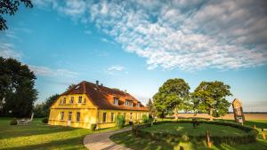 a large yellow house on a grassy field at Gut Rattelvitz - Parterre Ost in Gingst