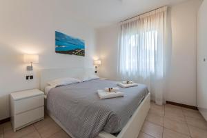 a white bedroom with a bed with two towels on it at Villa Bornico Marisa in Toscolano Maderno +15 photos