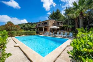 a swimming pool with chairs and a house in the background at Can Seguinot D'alt in Pollença