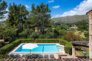 an outdoor swimming pool with an umbrella and chairs at Can Seguinot D'alt in Pollença