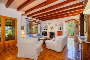 a living room with white chairs and a fireplace at Can Seguinot D'alt in Pollença