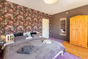 a bedroom with a large bed with a floral wallpaper at Das Atelier in Ihlow