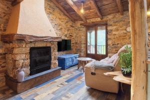 a living room with a stone fireplace and a couch at Miradoiro do Courel - Millares in Campelo