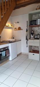 a kitchen with white tile floors and a counter top at La Maisonnette du Meslay in Fyé