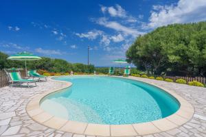a swimming pool with two chairs and an umbrella at Stella Marina Piscina e Vista Mare in Aglientu