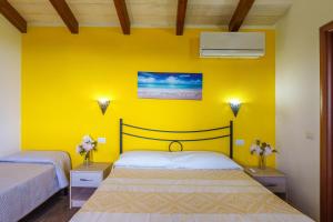 a bedroom with two beds and a yellow wall at Stella Marina Piscina e Vista Mare in Aglientu +26 photos
