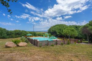 a swimming pool in a yard with a wooden fence at Stella Marina Piscina e Vista Mare in Aglientu