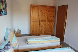 a bedroom with a bed and a wooden cabinet at Ferienwohnung Am Wehr in Georgensgmünd +2 photos