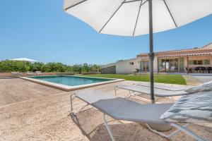 a patio with a chair and an umbrella and a swimming pool at Finca Laurel in Islas Baleares