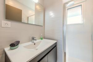 a white bathroom with a sink and a mirror at Les Terrasses de la Palud in Landéda +36 photos