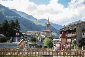 a village with a church and mountains in the background at Gîte Les Mélèzes in Termignon