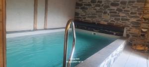 a swimming pool in a room with a stone wall at Gîte Les Mélèzes in Termignon