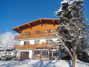 a house in the snow with a tree at Gästehaus Loithaler in Fügen