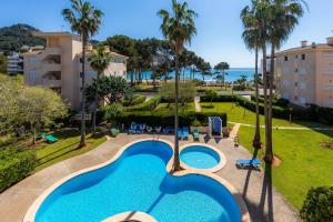 an aerial view of a resort pool with palm trees and the ocean at Oro del Mar iv apartamento 05 in Canyamel