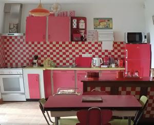 a kitchen with pink cabinets and a table in it at Aux souvenirs d'Antan in Broyes