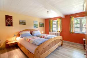 a bedroom with a wooden bed with orange walls at Friesisches Reetdachferienhaus in Bordelum