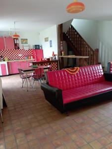 a living room with a red couch and a table at Aux souvenirs d'Antan in Broyes