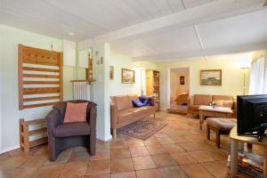 a living room with a couch and a tv at Friesisches Reetdachferienhaus in Bordelum