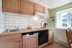 a kitchen with wooden cabinets and a sink at Friesisches Reetdachferienhaus in Bordelum