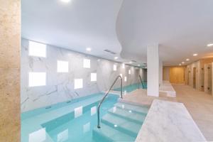 a pool in a hotel with a marble wall at Pula Golf Resort in Son Servera
