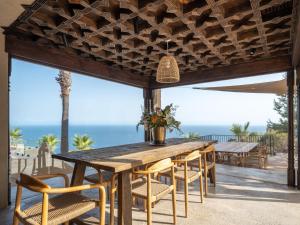 an outdoor dining room with a wooden table and chairs at Villa Rocca in La Herradura