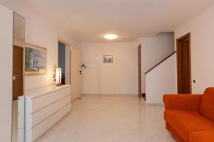 a living room with an orange couch and a hallway at Villetta a Castiglioncello in Castiglioncello