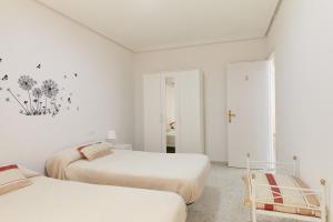 two beds in a room with white walls at Casa López in Baena