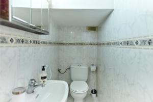 a white bathroom with a toilet and a sink at Casa López in Baena +21 photos