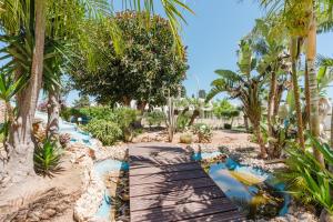 a wooden pathway through a resort with palm trees at Kairos San Vito Lo Capo in San Vito lo Capo