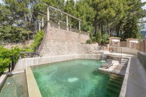 a swimming pool with a bench next to a stone wall at ses llebres in Bunyola