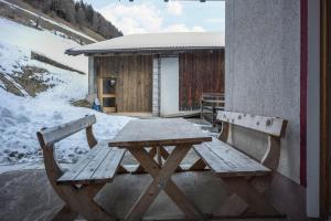 a wooden picnic table and bench in front of a building at Heiserhof App Kirsche in Racines