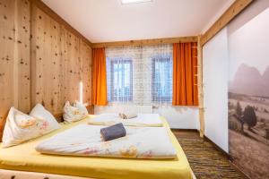two beds in a room with orange curtains at Heiserhof App Kirsche in Racines